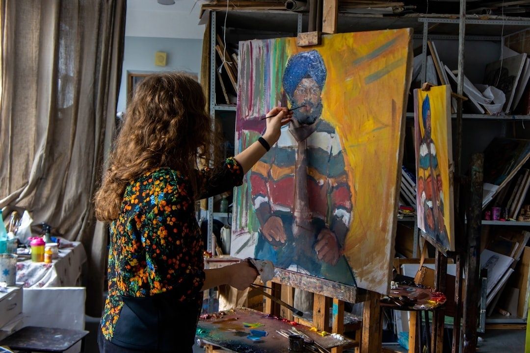 Malerin arbeitet in einem Atelier an einem großformatigen Porträt