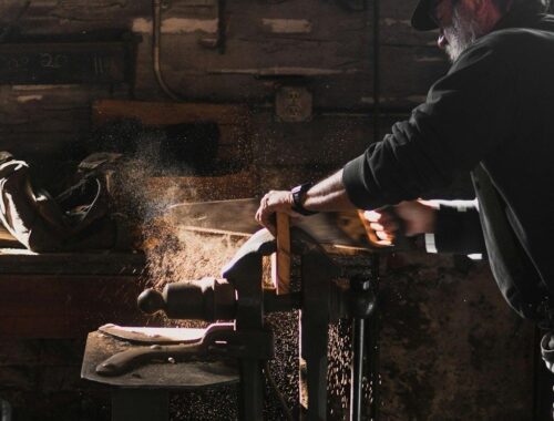 Handwerker bearbeitet Holz in einer staubigen Werkstatt